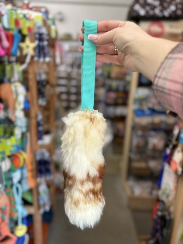 Szarpak dla psa Psarvard Tika z naturalnego futra owczego i niebieską taśmą trzymany w dłoni