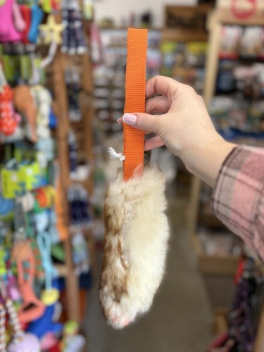 Szarpak dla psa Psarvard Tika z futra owczego i pomarańczową taśmą trzymany w dłoni